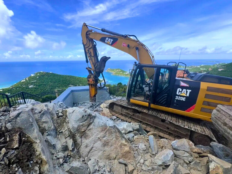 Excavator with hydraulic breaker cutting pool excavation into hillside rock above the Caribbean Sea, private estate construction St. John USVI, by Aquatics International Group