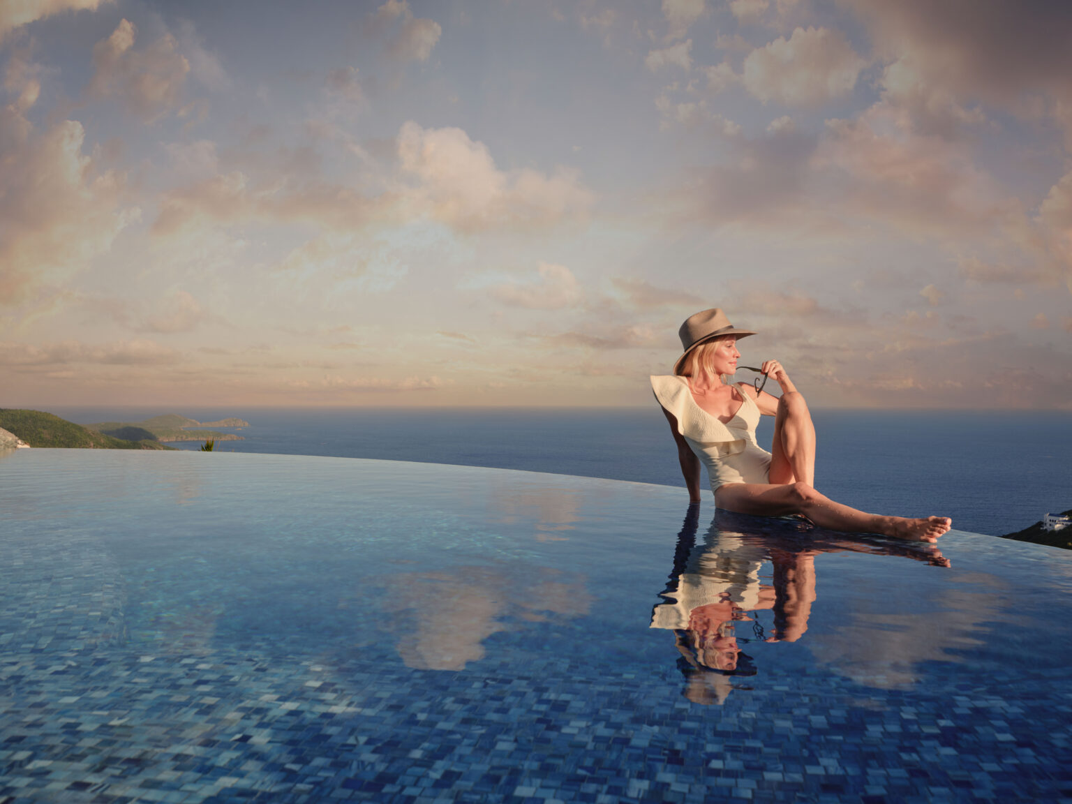 Guest relaxing on the edge of an infinity pool at sunset overlooking the Caribbean Sea, private estate pool St. John USVI, by Aquatics International Group
