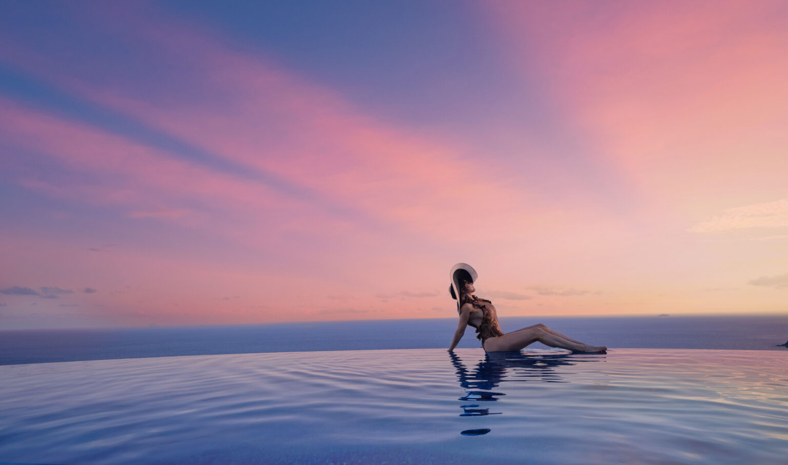 Guest lounging on the edge of an infinity pool at sunset overlooking the Caribbean Sea, private estate pool St. John USVI, by Aquatics International Group