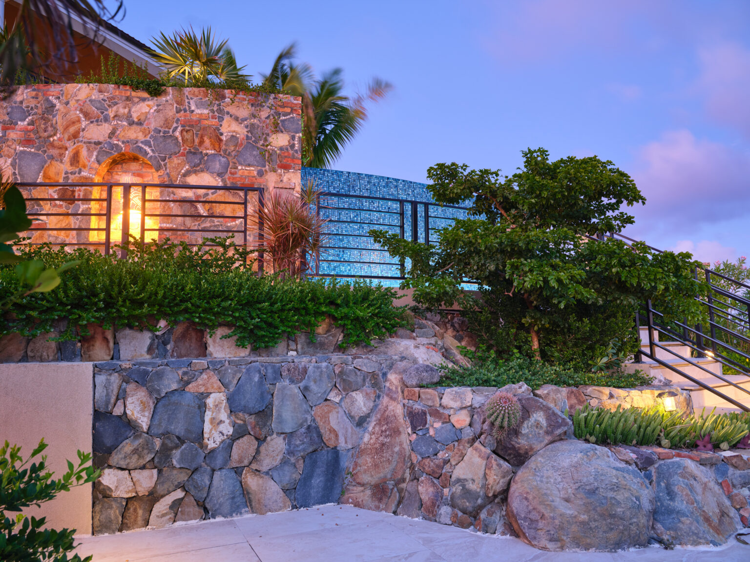Natural stone walls and landscape lighting at dusk at a hillside estate entry, private estate pool St. John USVI, by Aquatics International Group