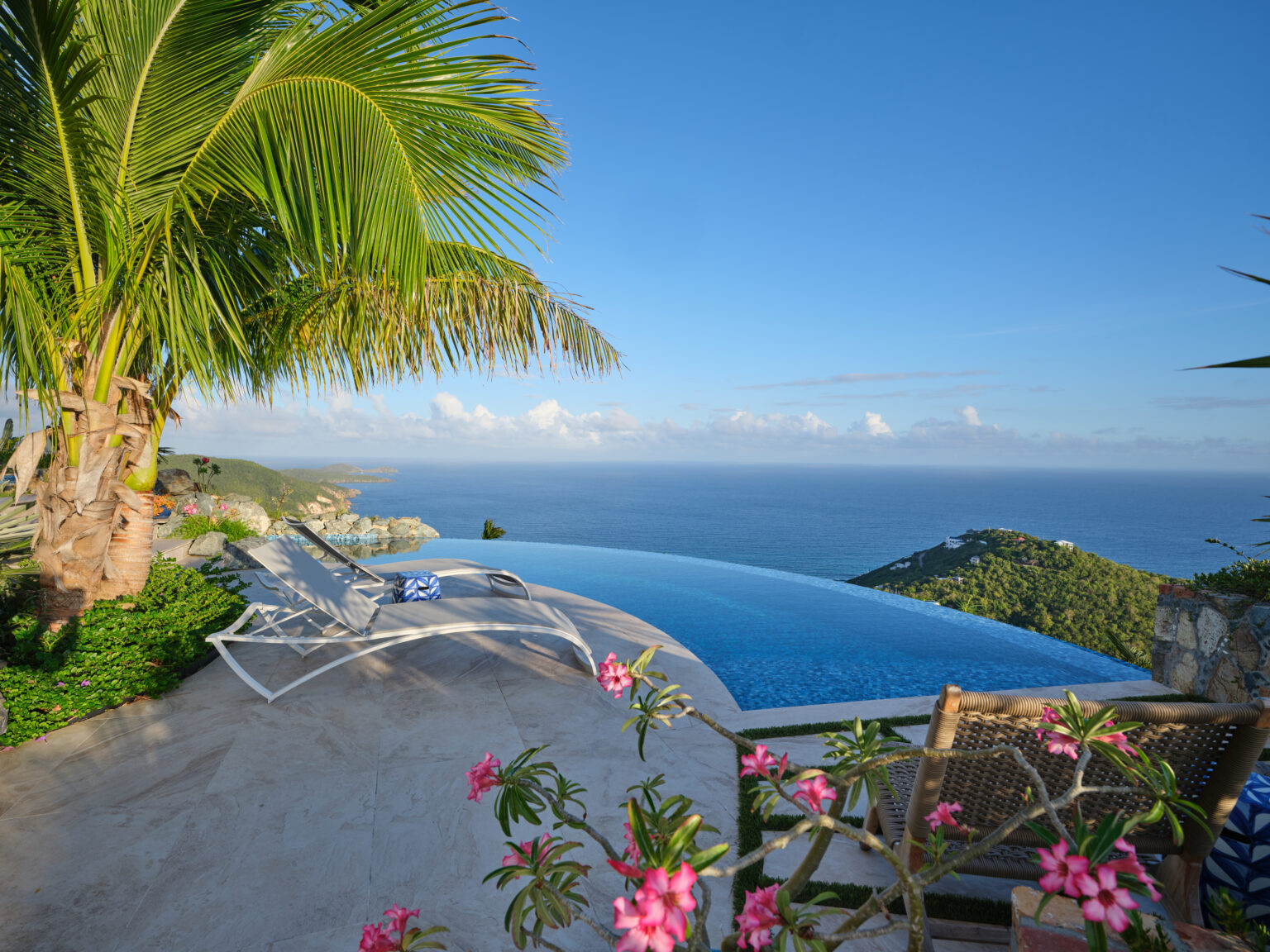 Infinity pool deck with lounge chairs, palm trees, and tropical flowers overlooking the Caribbean Sea, private estate St. John USVI, by Aquatics International Group